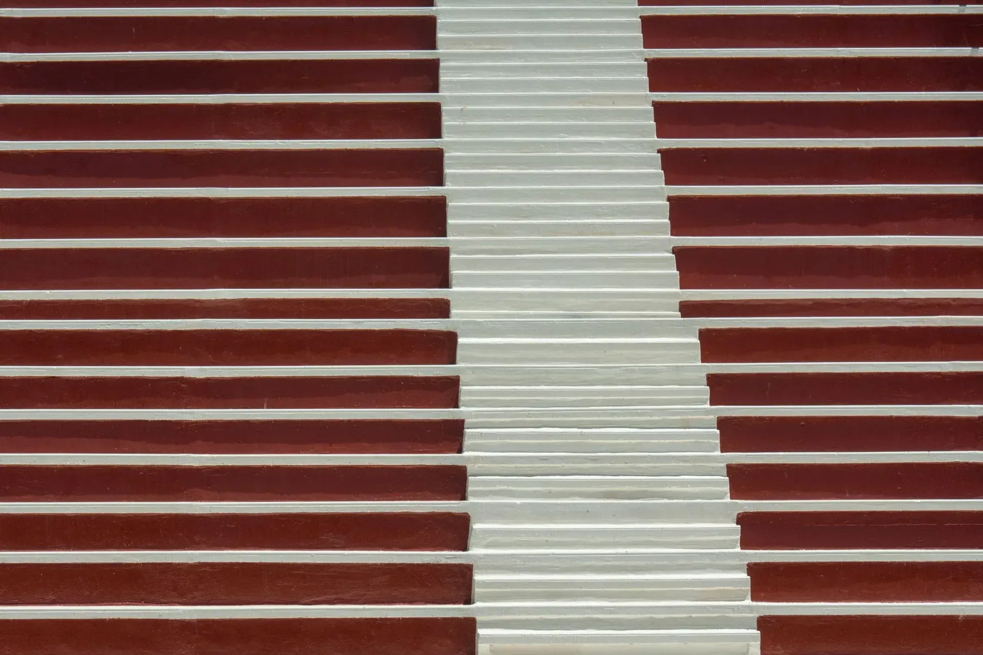 Rows of empty stadium seating either side of a pale concrete stairway.