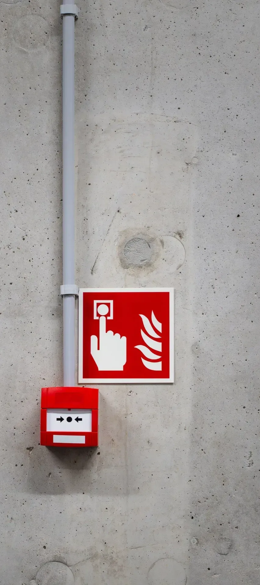 Red manual call point on a concrete wall