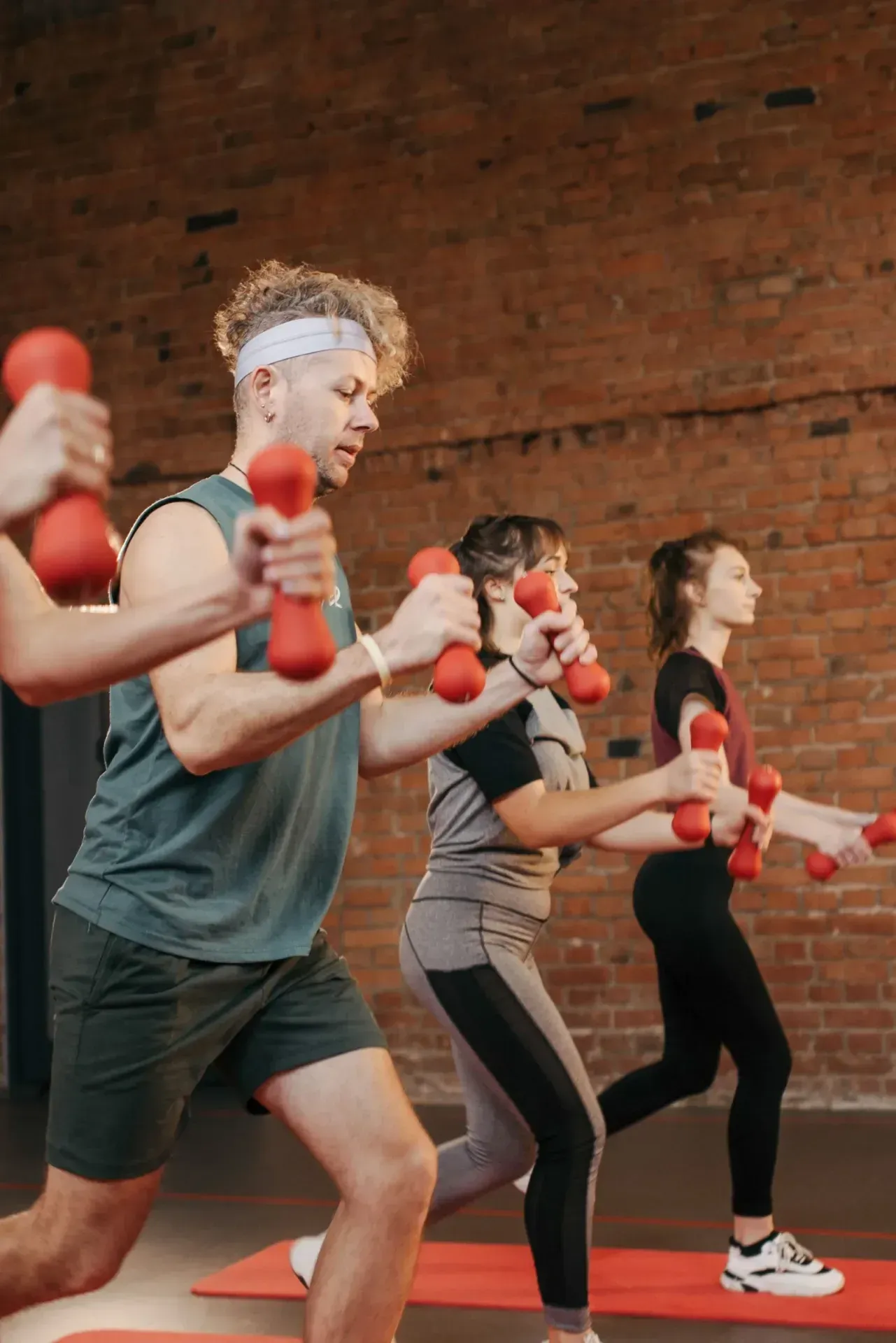Three people in an exercise class with hand weights.