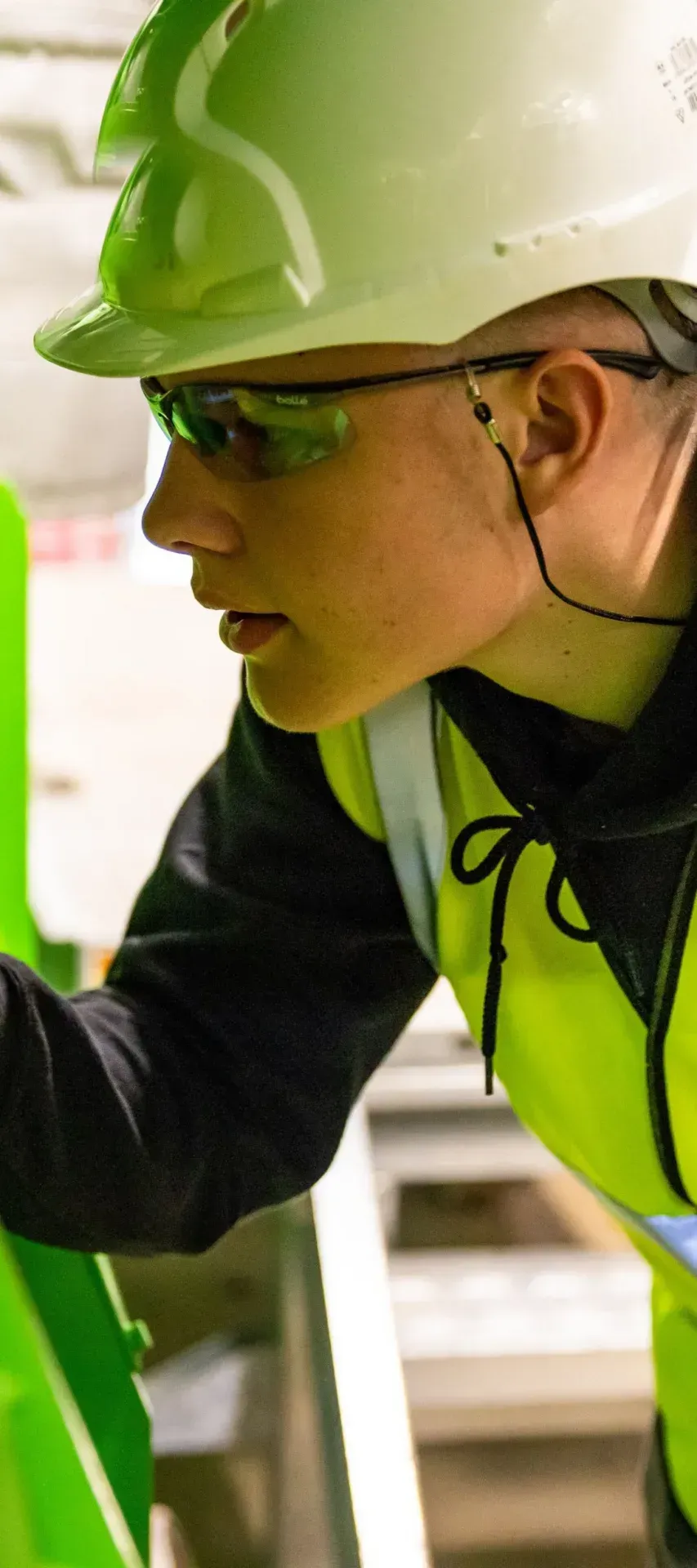 An engineer in a hard hat and safety glasses inspecting plant