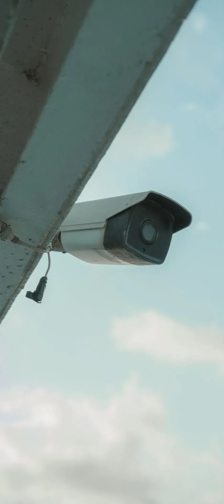 White CCTV camera mounted under the eaves of a building