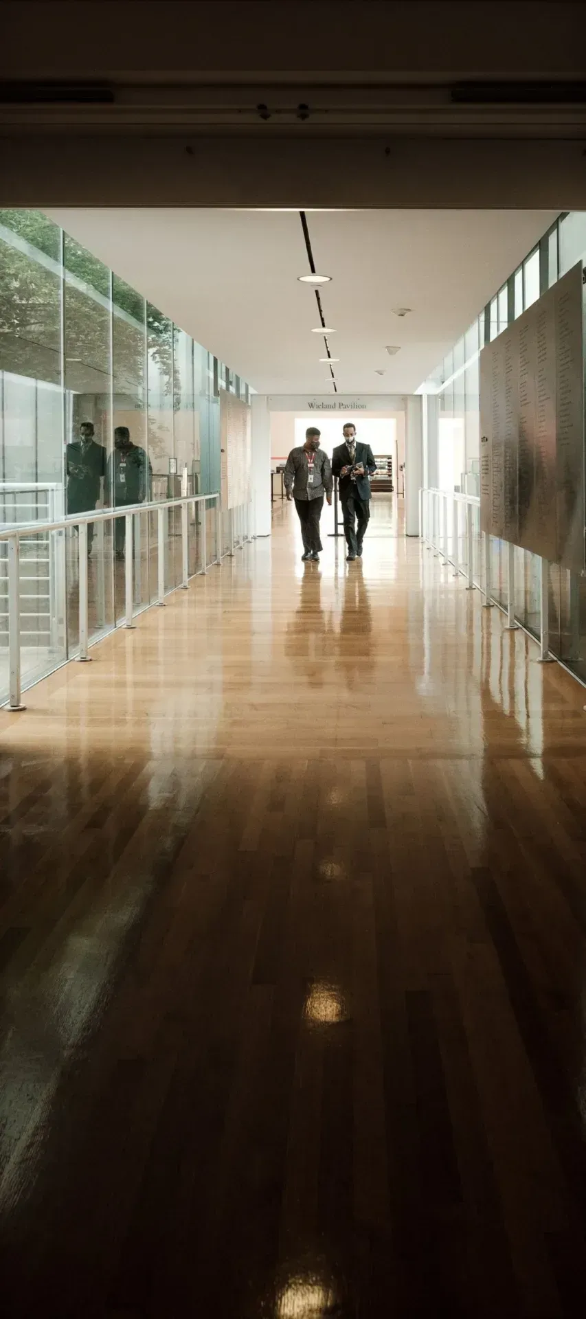 Staff walking along a bright corridor with glass balustrades