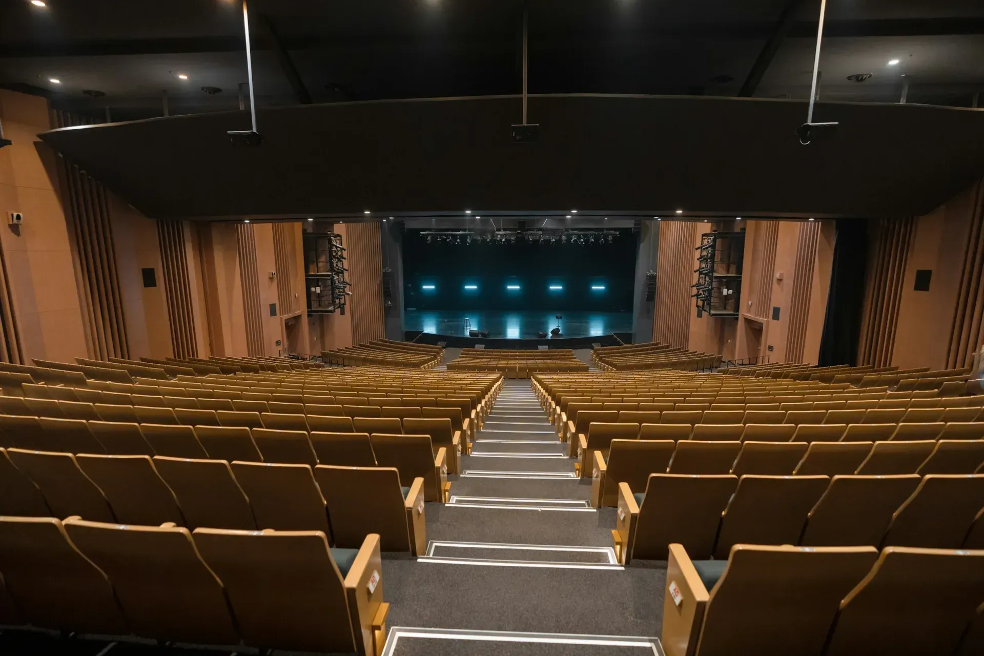 An empty auditorium with rows of seats running down to a lit stage.