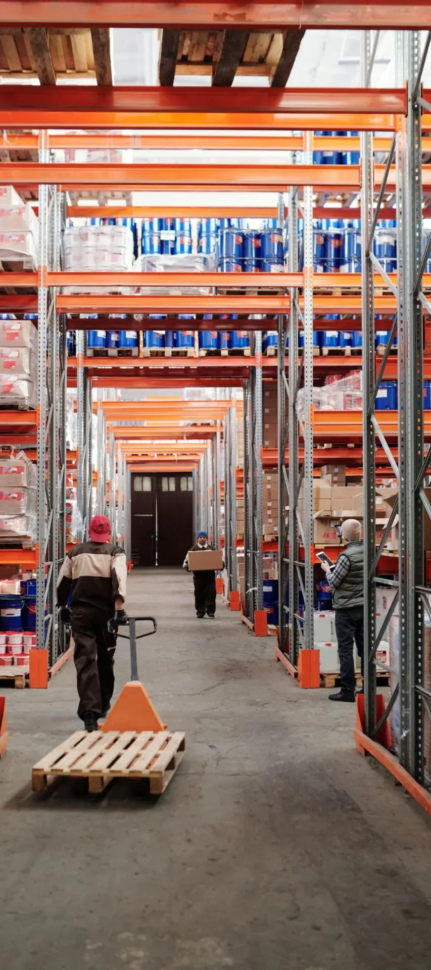 Warehouse staff moving stock between tall pallet racks