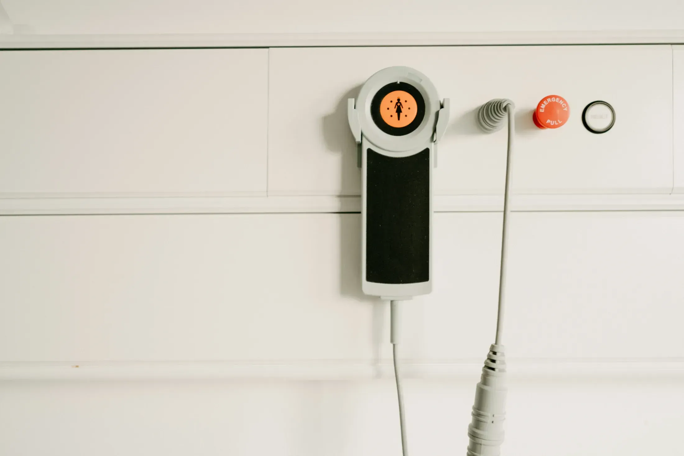 Nurse call handset beside an emergency pull control and reset button