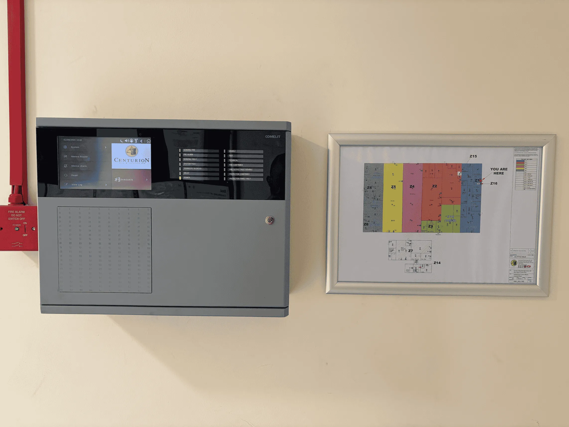 Comelit fire alarm panel showing the Centurion logo, beside a framed zone plan