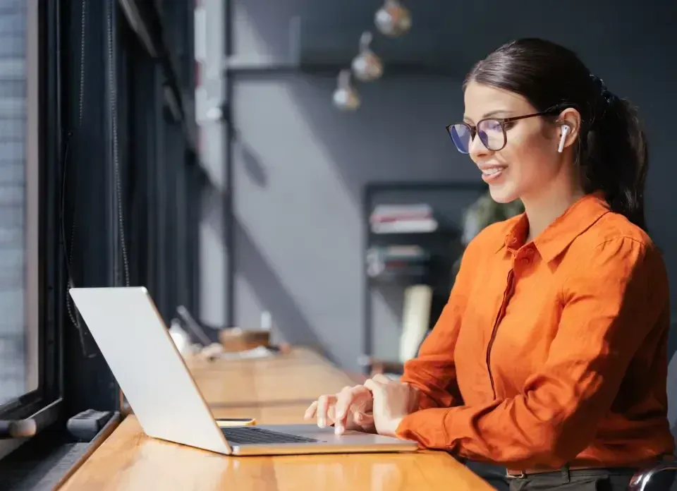 A person working on a laptop at a window desk in a modern office