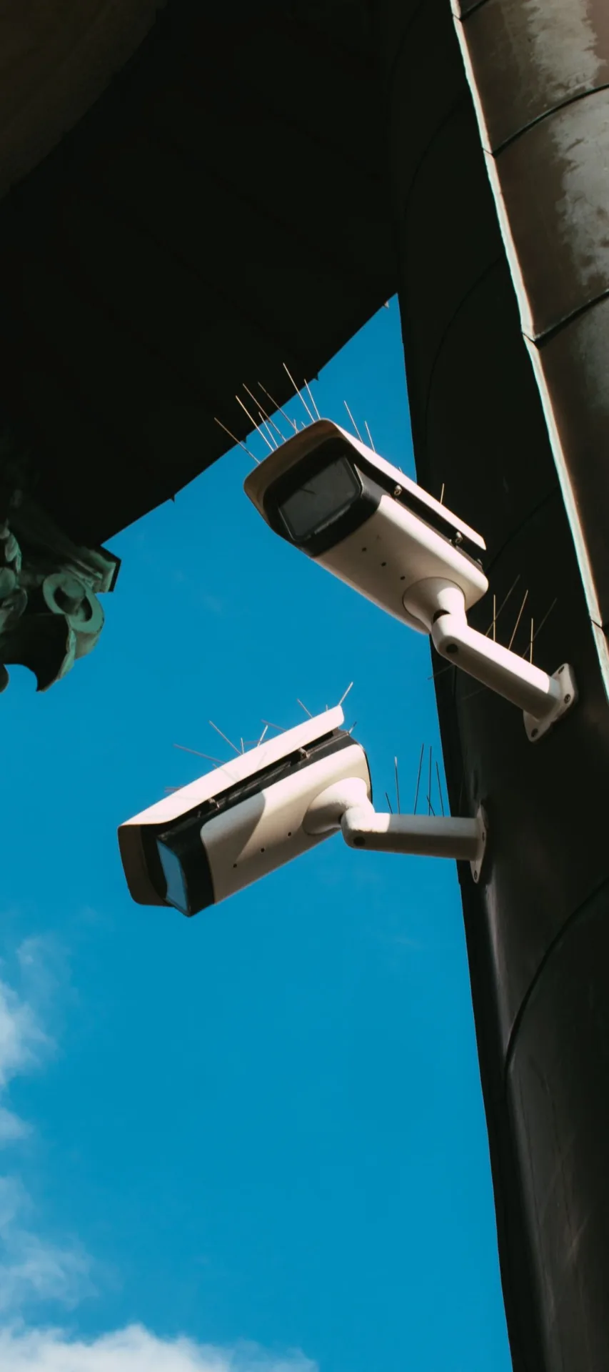 Two CCTV cameras on a pole against a clear sky