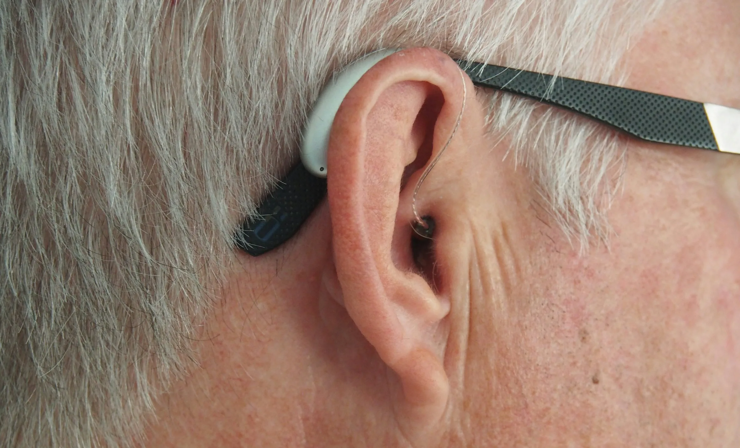 Behind-the-ear hearing aid on an older man, close-up