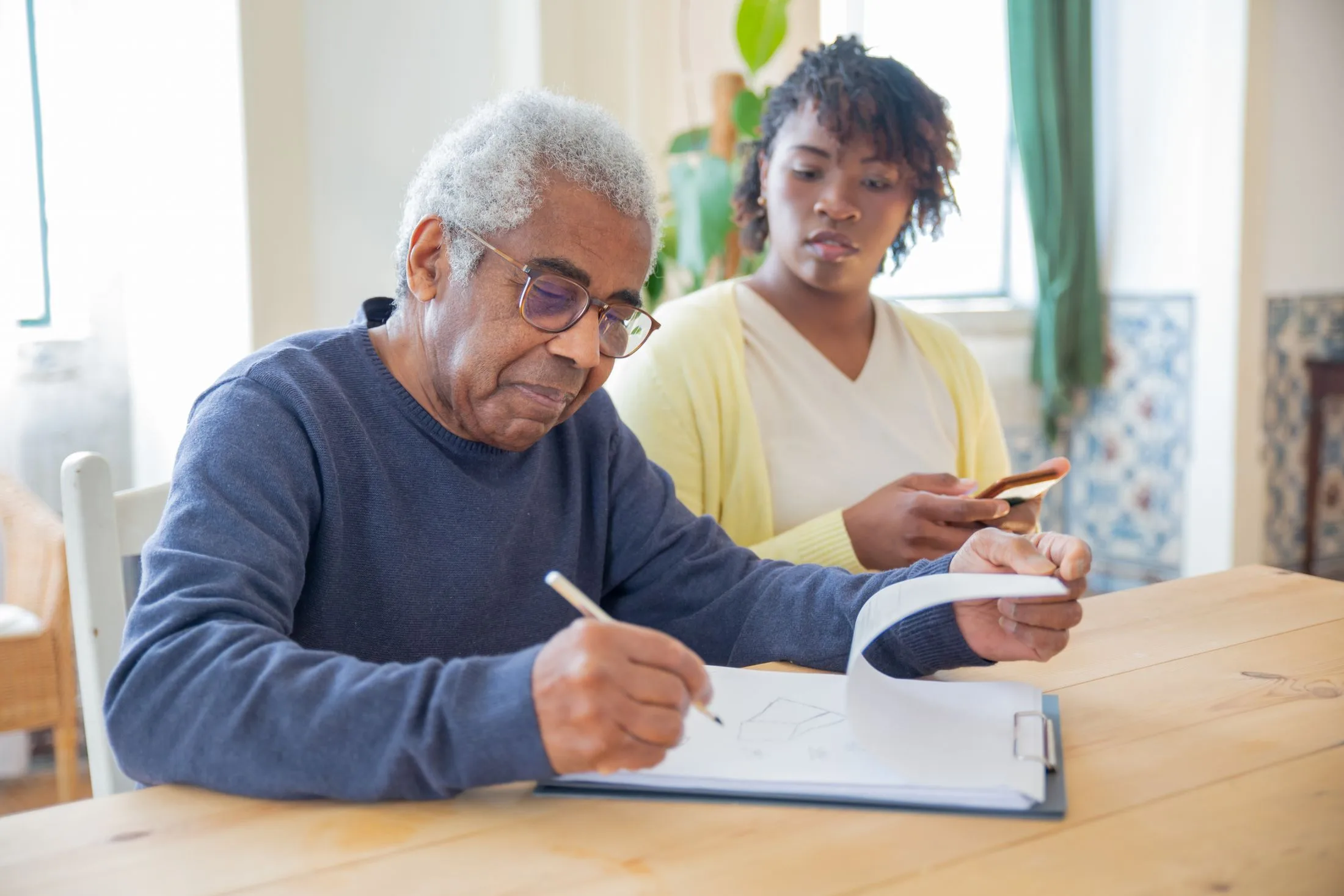 An older man reviewing paperwork with another person